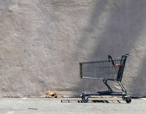 Empty shopping cart against a blank grey wall
