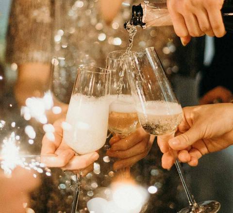 Champagne being poured into three glasses held by people at a celebration