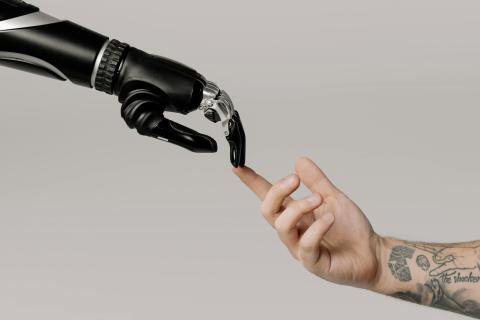 Human hand touching the a robot hand with its index finger 