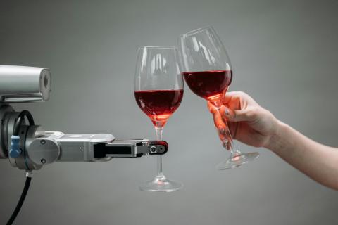 Human hand holding a wine glass and cheersing a robot holding a wine glass 